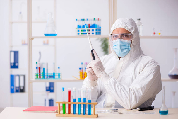 Νεαρός άνδρας χημικός που εργάζεται στο εργαστήριο κατά τη διάρκεια πανδημίας - Φωτογραφία, εικόνα
