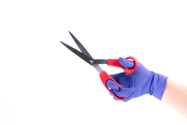 Hand in a latex glove holding scissors on white wall with copy space. Cut prices during a quarantine. - Photo, Image