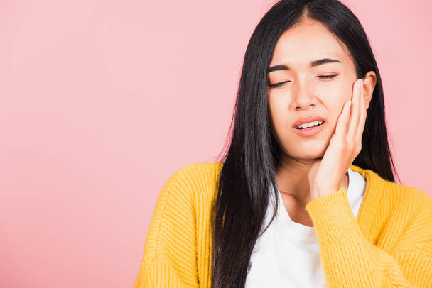 Portrait of Asian beautiful young woman suffering from toothache, female terrible strong teeth pain problem pressing hand to chin, studio shot isolated on pink background, Dental health care concept - Foto, imagen
