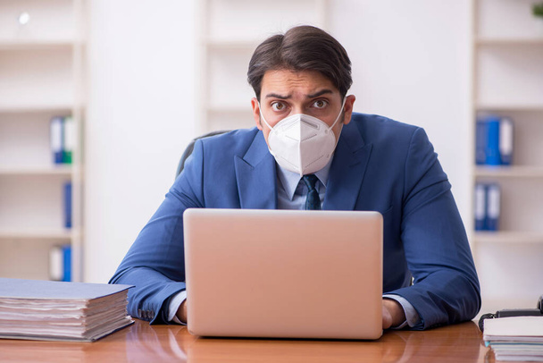 Junger Geschäftsmann arbeitet während der Pandemie im Büro - Foto, Bild