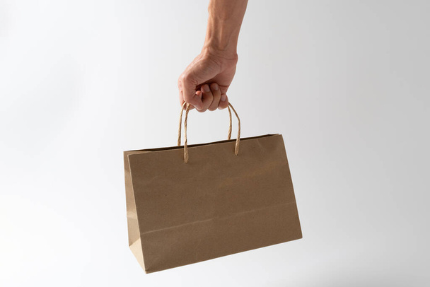 Man holding paper shopping bag on whie background - Foto, afbeelding