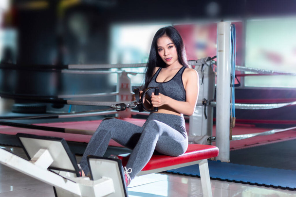 Fitness Asian women performing doing exercises training with rowing machine (Seat Cable Rows Machine) in sport gym interior and fitness health club with sports exercise equipment Gym. - Fotó, kép