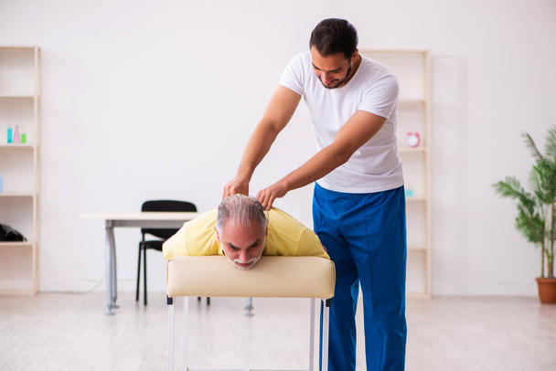 Velho paciente masculino visitando jovem médico chiropractor - Foto, Imagem