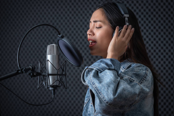 Happy cheerful pretty smiling of portrait of young Asian woman vocalist Wearing Headphones recording a song front of microphone in a professional studio - Foto, imagen