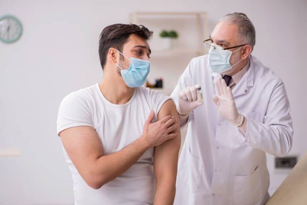 若い男性患者訪問古い男性医師で予防接種ce - 写真・画像