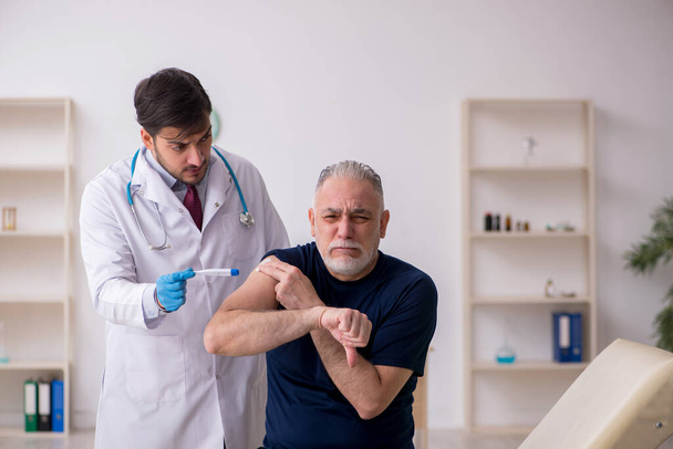 Old male patient visiting young male doctor in vaccination conce - Foto, Imagem