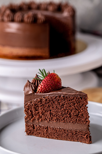 Slice of delicious homemade chocolate cake soft fudge topping with strawberry on white plate, closeup. - 写真・画像