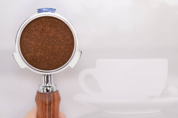 Ground coffee powder in portafilter with space for cafe text and coffee mug background. - Photo, Image