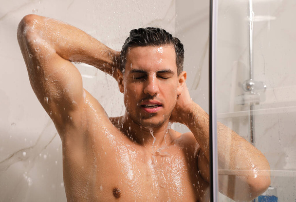 Handsome man taking shower at home. Morning routine - Фото, изображение