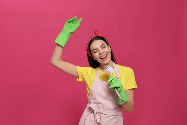 Young housewife with brush on pink background - Foto, Bild