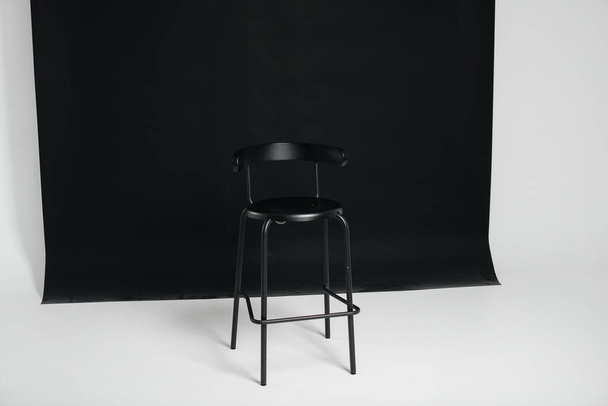 A stylish black chair stands on a black background in the studio room. The concept of a vacancy or an interview. Cinema, director's chair. - Fotó, kép