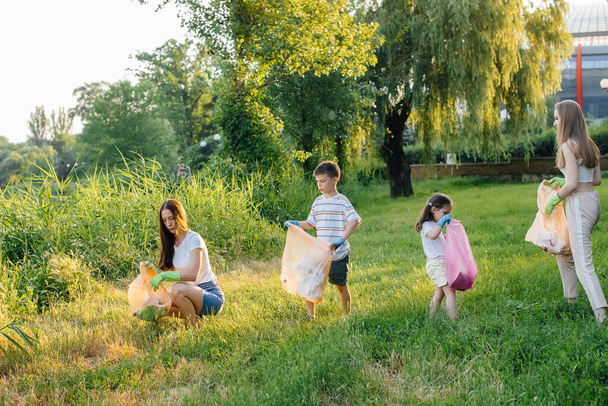 A group of girls with children at sunset are engaged in garbage collection in the park. Environmental care, recycling. - Foto, Imagem