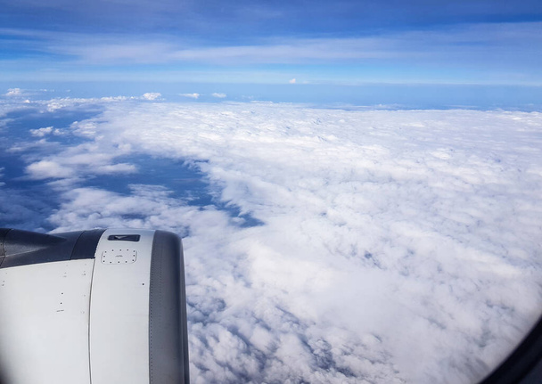 Widok z okrągłego okna samolotu na białe chmury śniegu, przelatujące nad chmurami, koncepcja wolności i podróży. - Zdjęcie, obraz