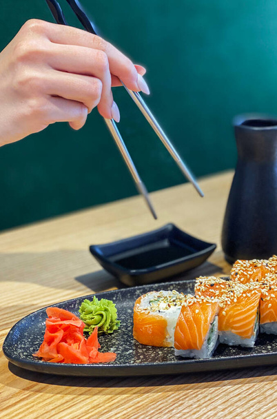 Jedzenie sushi w japońskiej restauracji, ręka z pałeczkami  - Zdjęcie, obraz