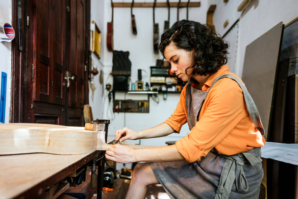 kobieta luthier podejmowania gitary w swoim warsztacie instrumentu muzycznego - Zdjęcie, obraz