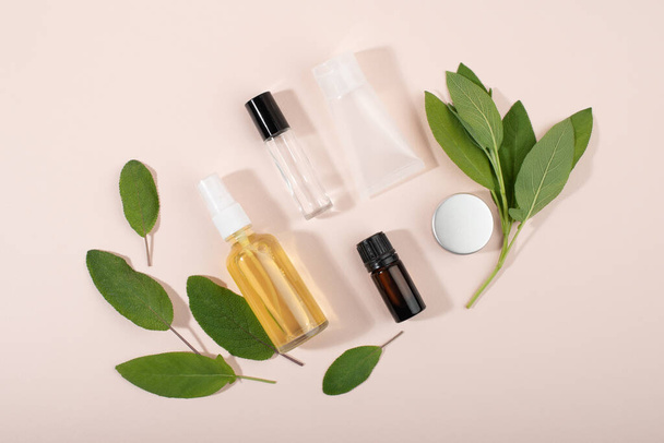 Cosmetic containers and herbal sage leaves on light background flat lay top view. Cosmetics SPA branding mock-up. Organic beauty product concept. - Φωτογραφία, εικόνα