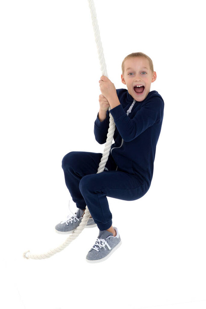 Active smiling boy hanging on swing rope - Foto, afbeelding