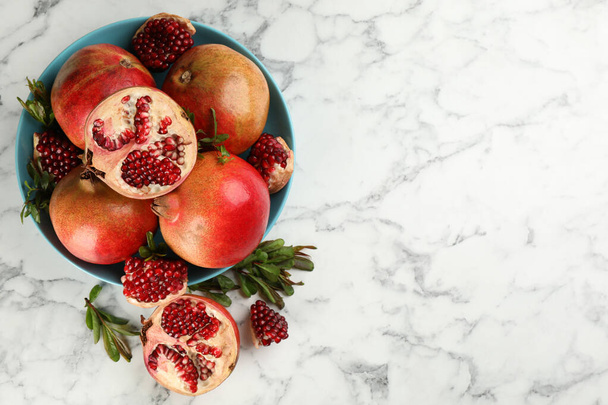 Delicious ripe pomegranates on white marble table, flat lay. Space for text - 写真・画像