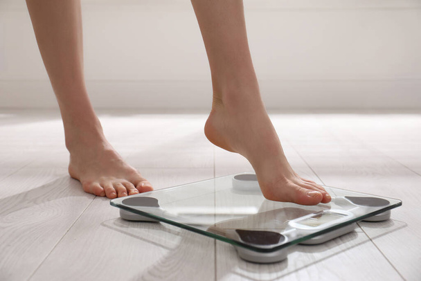 Woman stepping on floor scales indoors, closeup. Weight control - Φωτογραφία, εικόνα