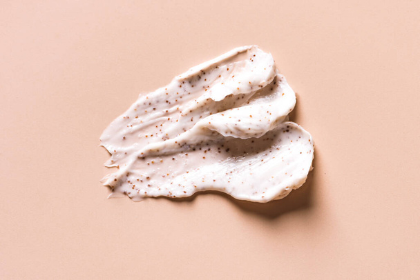 Sample of natural scrub on nude pink background. Peeling cream with microcapsules. Peach or coffee scrub smear. - Photo, Image