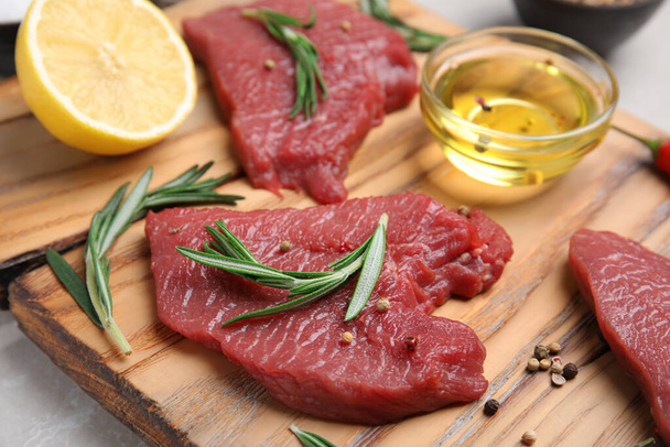 Fresh raw meat steaks and spices on wooden board, closeup - Foto, afbeelding