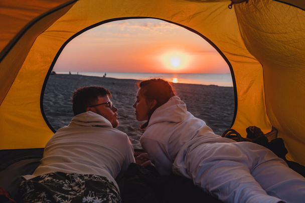 couple sleeping in camping tent looking at sunrise. hiking concept. sea beach - Photo, Image