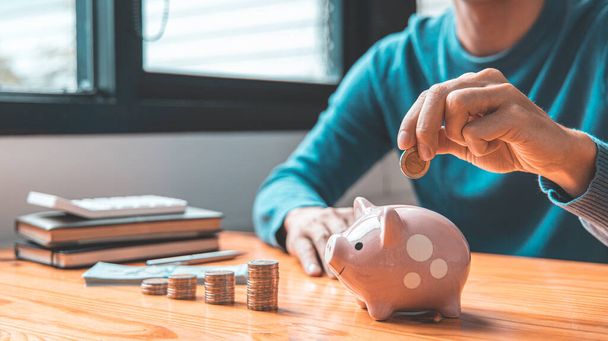Man puts a coin dollar in a piggy bank, Saving money for future growth and knowing how to manage your spending wisely, Saving money for business growth or long-term profitability. - Photo, Image