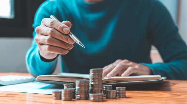 Man counts the coins piled up on the table in preparation to save money, Take note of household financial expenses, Saving money for future growth and knowing how to manage your spending wisely. - Photo, Image