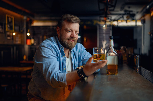 Muž nalévá alkohol na pult v baru. Jeden muž odpočívající v hospodě, lidské emoce a volnočasové aktivity - Fotografie, Obrázek
