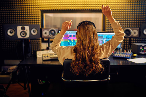 Ingegnere del suono femminile al mixaggio consol, vista posteriore, registrazione degli interni dello studio sullo sfondo. Sintetizzatore e mixer audio, luogo di lavoro musicista, processo creativo - Foto, immagini