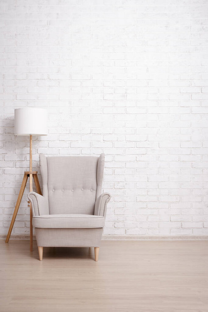 Fotel i lampa z przestrzenią do kopiowania na ceglanym tle ściany - Zdjęcie, obraz