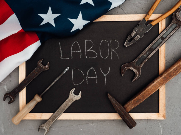 LABOR DAY. Hand tools and the Flag of the United States of America lying on the table. View from above, close-up. Congratulations to family, relatives, friends and colleagues. National holiday concept - Foto, afbeelding