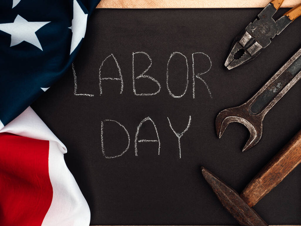 LABOR DAY. Hand tools and the Flag of the United States of America lying on the table. View from above, close-up. Congratulations to family, relatives, friends and colleagues. National holiday concept - Photo, image