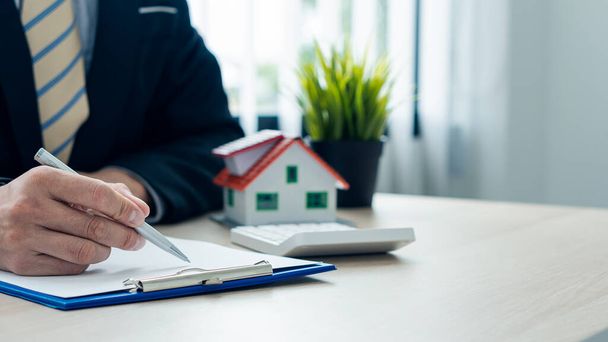 Immobilienmakler arbeiten an Papieren und Hausplänen, die auf dem Tisch liegen, um Kauf- und Leasingverträge mit Finanzierung anzubieten. - Foto, Bild