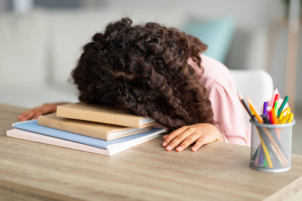 Ylityöllistetty afrikkalainen amerikkalainen koulutyttö lepää pää pää pää pöydällä, väsynyt läksyjä, istuu kotona olohuoneessa sisustus - Valokuva, kuva