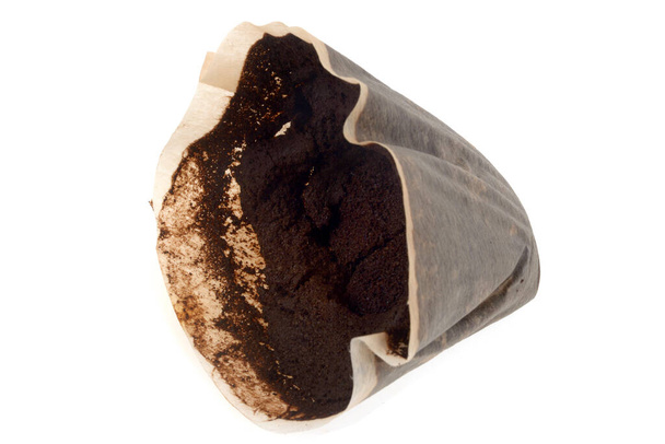 Used coffee grounds in a paper filter close up on white background  - Foto, imagen