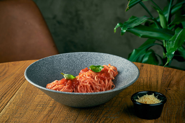 spaghetti pasta with tomato sauce and basil in a gray plate. italian cuisine - Foto, Imagem