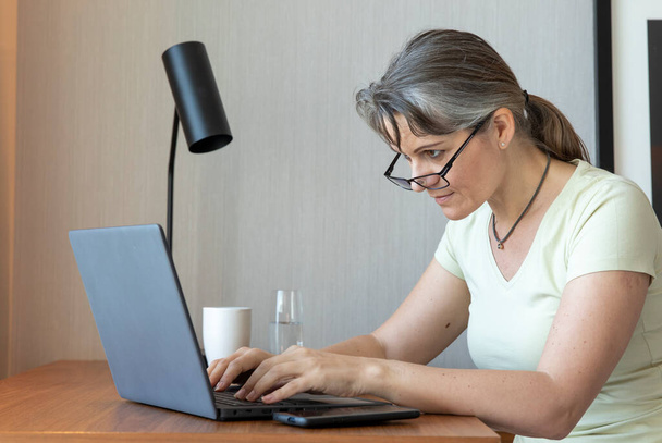 Жінка середнього віку працює вдома
 - Фото, зображення