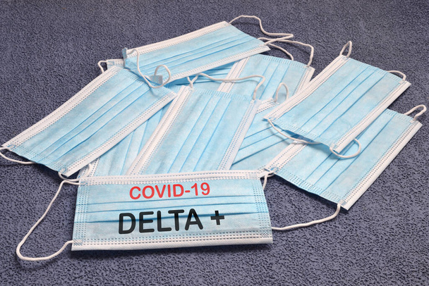 Coronavirus Covid-19 'un bir çeşidi olan Covid-19 Delta + metin ile virüse karşı antiviral maskeler. Covid-19 virüsüne karşı koruma kavramı. - Fotoğraf, Görsel