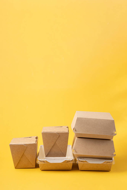 Disposable food delivery boxes on yellow background - Fotó, kép