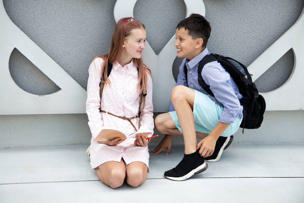 Bambini adolescenti, scolari ragazzo e ragazza su sfondo di muro di cemento. Bambini che ridono con gli zaini della scuola sulle spalle - Foto, immagini
