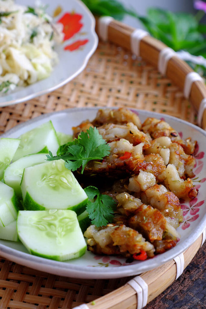 Вьетнамское вегетарианское блюдо на обед с домашней едой, веганское мясо из пшеничной муки и рисовая мука нарезанная в ломтик, затем жареная с цитронеллой, соус. Вкусная тарелка еды с нарезанным огурцом на подносе - Фото, изображение