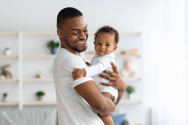 szczęśliwy Afroamerykanin ojciec przytula jego uroczy noworodek syn w domu - Zdjęcie, obraz