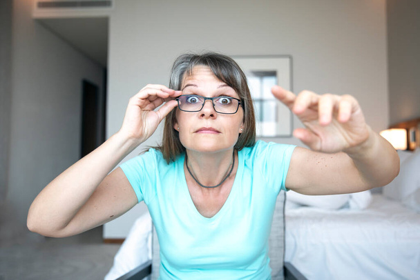жінка середнього віку, що лежить, щоб полагодити окуляри, щоб побачити краще
 - Фото, зображення