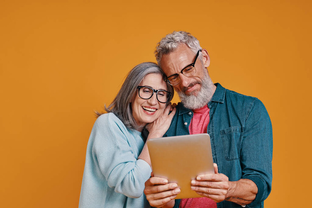 Happy senior couple smiling and using digital tablet and smiling - Foto, Imagem