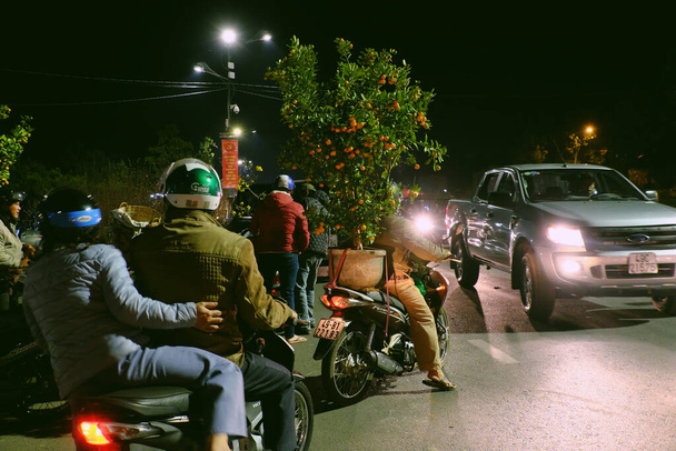 DA LAT, VIET NAM- JAN 24, 2020: Πλήθος δρόμους την παραμονή, οι άνθρωποι μεταφέρουν kumquat δέντρο για να κάνουν στολίδι δέντρο σε Tet διακοπές τη νύχτα υπαίθρια αγορά γεωργός - Φωτογραφία, εικόνα