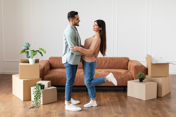 Счастливые мужчина и женщина обнимаются в своей новой квартире - Фото, изображение