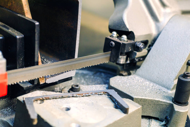 Bandsägemaschine zum Sägen von Metallprodukten. Teil wird abgesägt und liegt in den Spänen neben - Foto, Bild