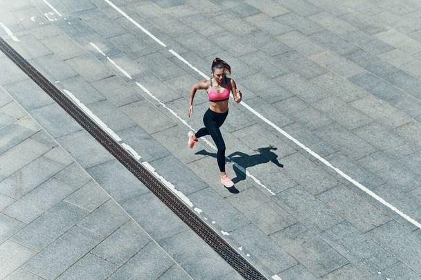 Top view of attractive young woman in sports clothing running outdoors - Photo, Image