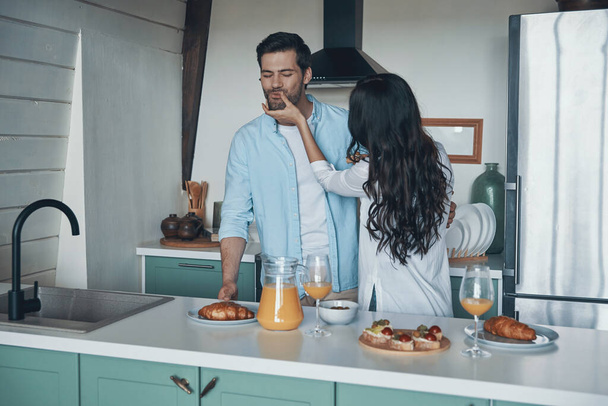 Beautiful young couple tasting breakfast while spending time in the kitchen - Photo, Image